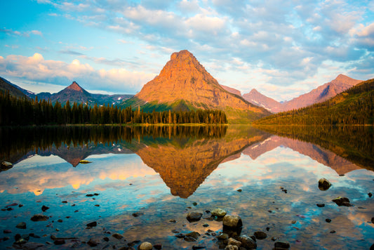 A scene from a crisp Montana morning in Glacier National Park. The still air makes the lake into a mirror that almost seems like another dimension in the quiet mountain air. Nothing stirs, all is calm. Sure to bring serenity to any space.